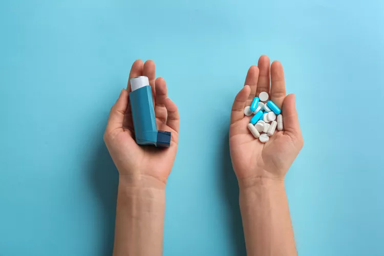 Two hands with an inhaler in one and pills in the other for patient market research